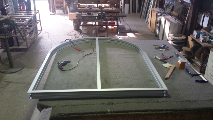 arched clear anodise aluminium fixed lite window - being assembled